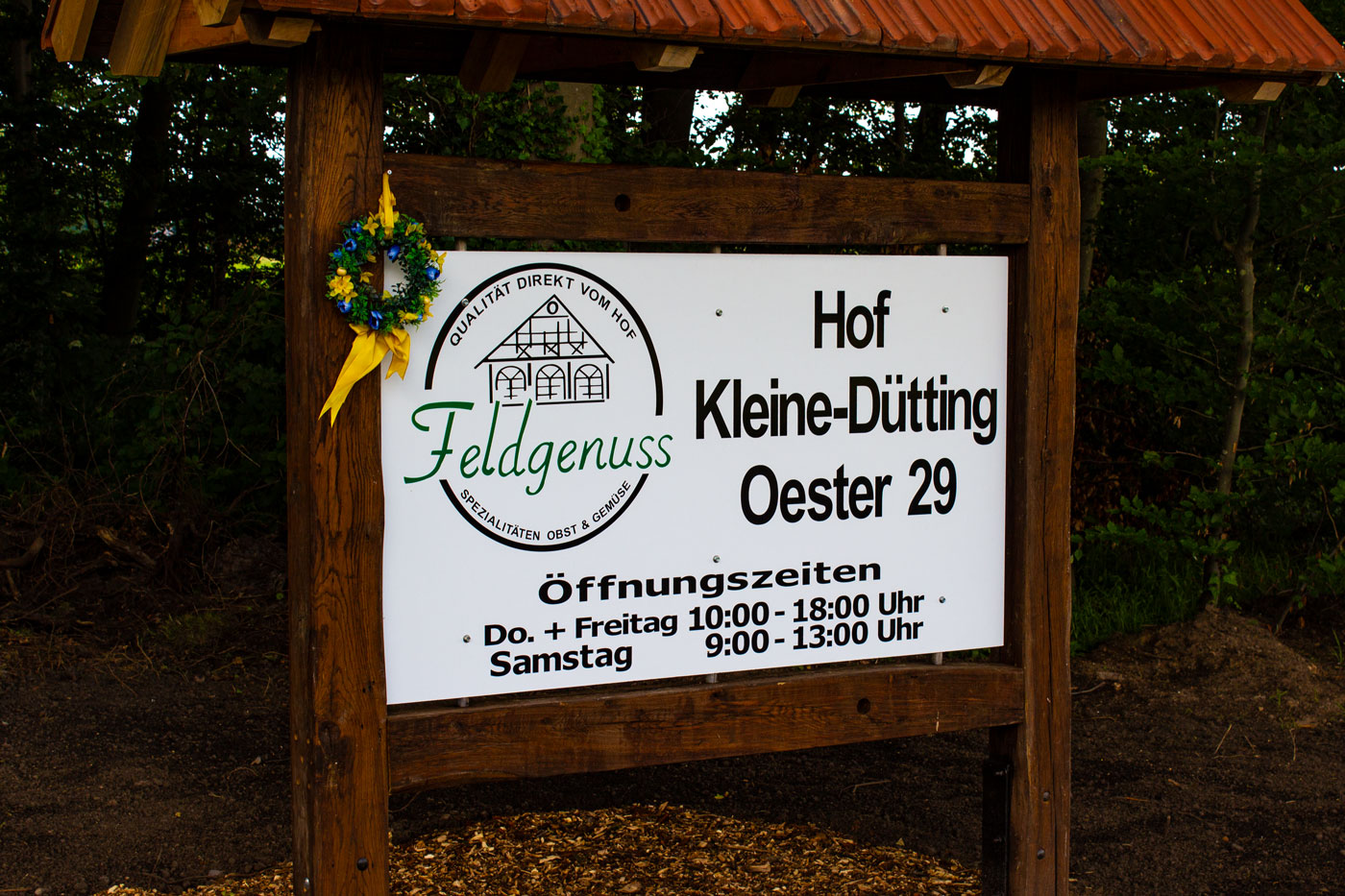 Hofschild Kleine Dütting das vor der Einfahrt steht mit krleinem Blumenkranz